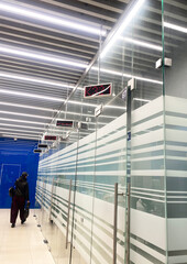 Modern bank branch interior featuring sleek glass partitions, illuminated ceiling, and digital displays, creating a professional and inviting atmosphere for customers