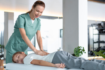 Physiotherapist performing back massage on child during rehabilitation session