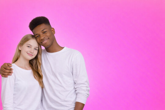 Interracial teenage couple portrait on pastel pink background modern valentine lifestyle image