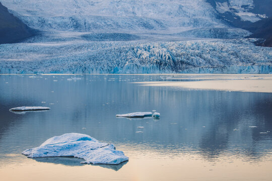 View of icy chunks drift on the glacial lagoon, reflecting the majestic Vatnajokull glacier under a serene sky, Fjallsarlon, Vatnajokull glacier, Iceland.