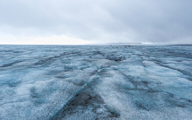Surface of melting ice, with puddles of icy water and patches of volcanic ash mud. Panoramic view from the ice cap. Expedition on the Langj&ouml;kull or 'long glacier', second largest glacier of Iceland.