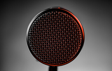 A microphone stands in focus under a bright light. The scene shows a venue filled with energy as musicians perform. The setting captures the excitement of live music.