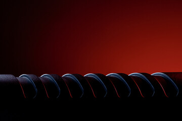 A metallic spiral is shown clearly with a focus on the curves and contours. The background is dark with red light creating an interesting atmosphere around the subject.