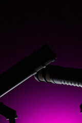 Two microphones are positioned against a purple background, ready for a performance. The scene highlights the importance of sound in live events, preparing for musicians.