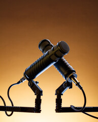 Two microphones are set on a stand against a warm background. They are ready for a sound check, suggesting preparation for a music event or performance.