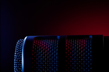 A microphone is positioned in front of a dark background. Colored lights create a red and blue effect around the microphone. The scene suggests a music or podcast recording session.