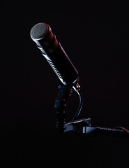 A microphone is mounted on a stand with cable connections. This setup is ready for recording sound. The background is dark, highlighting the equipment used in music production.