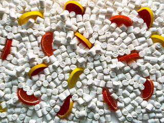 The background image. Food, sweets. Scattered small white marshmallows and slices of marmalade. View from above.