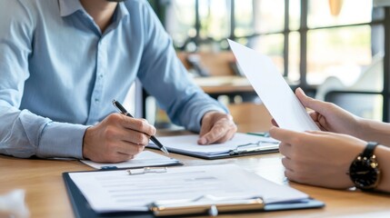 Two men in business attire discussing paperwork at a table.