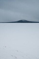 Winter view of lake Zuratkul on a grey day with mountain Lukash in the background, South Ural, Russia