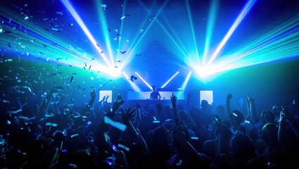 Obraz premium A lively crowd dances under bright blue and green lights at a music concert. Excitement and energy fill the atmosphere as confetti falls from above.