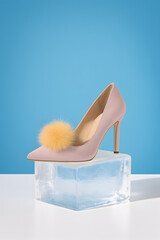 Elegant pink high heel with pom pom on a white box