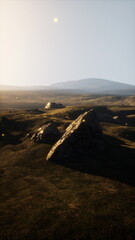 A grassy plain with a hill in the distance under a clear sky.