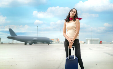 Happy Asian woman traveler with suitcase at the airport with airplane background. Concept of summer vacation, international travel, aviation, and global tourism lifestyl