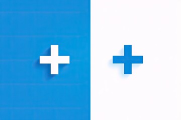 Fototapeta premium Two plus signs, one white, one blue, against a color-blocked backdrop of blue and white