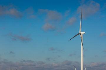 A wind turbine with rotating arms against a blue sky.