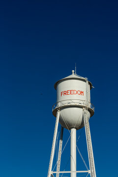 A tall water tower, view from below, painted with the name Freedom.