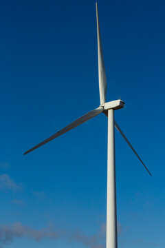A wind turbine with rotating arms against a blue sky.