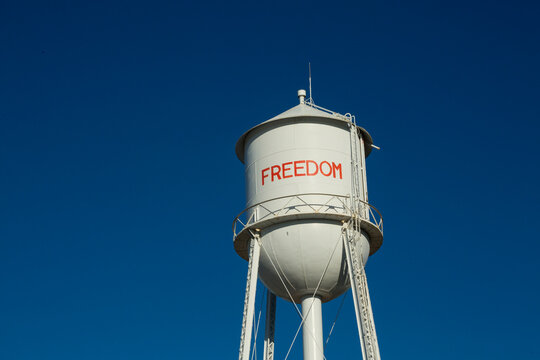 A tall water tower, view from below, painted with the name Freedom.