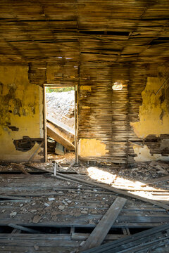 A shell of a building, a derelict house interior, exposed timbers and peeling paintwork, foreclosure, economic ruin.