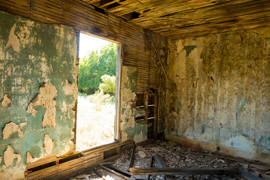 A shell of a building, a derelict house interior, exposed timbers and peeling paintwork, foreclosure, economic ruin.