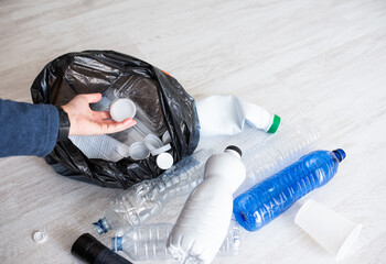 Hand putting white cap in black bag with bottles, bright waste management, recycling app, or eco campaign