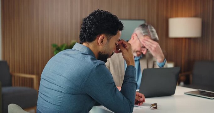Business, people and stress with laptop in office for bad news, finance mistake and overwhelmed. Disappointed, men and discussion with financial error, company bankruptcy and teamwork of funding fail