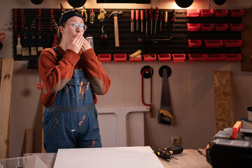 Shocked Amazed Woman joiner wears workwear in workshop scene with tools hanging on wall has shock...