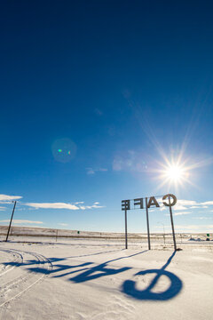 Cafe sign, large letters and a shadow on the ground.