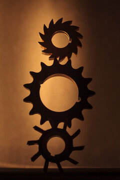 Wheels as gears, a balanced stack of three different metal cog wheels with different shaped exterior shapes.
