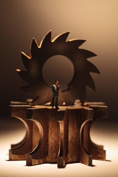 A toy model of a Businessman standing by three stacked cog wheels with different gearing.