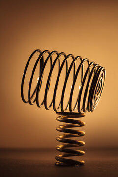 Large metal coiled spring balancing on a smaller spring, studio shot.