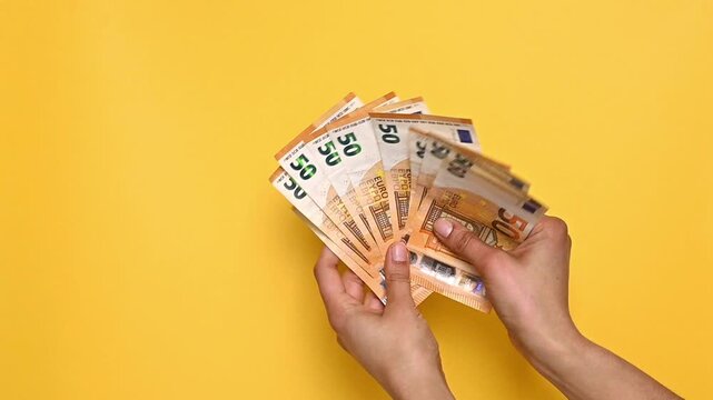Woman hands on a yellow background counting a euro banknotes, calculates his income, salary, earnings ,Economy and savings, Taxes and finance, Payments and insurance, Cash and coins