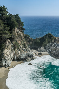 Julia Pfeiffer Burns State Park, elevated view over the beach, waves breaking, steep cliffs and a waterfall.