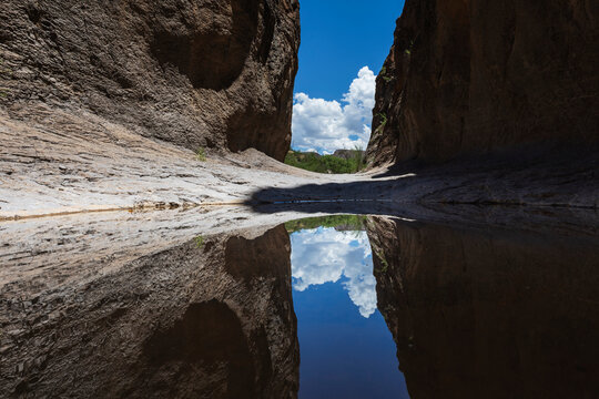 A narrow slot canyon with a mirror reflection in the water near Lajitas.