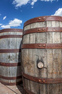 Rustic wooden barrels with metal bands under a bright blue sky in Hill City, South Dakota, capturing historic charm and Western character.