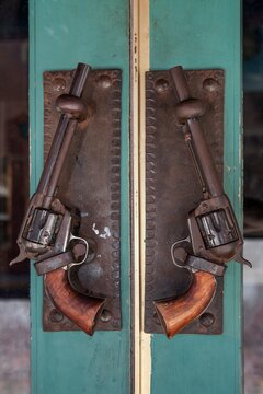 Close-up of antique revolvers repurposed as decorative door handles.