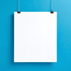 A crisp, white sheet of blank paper is pinned to a vibrant blue wall, creating a striking contrast that draws the eye and invites creativity.