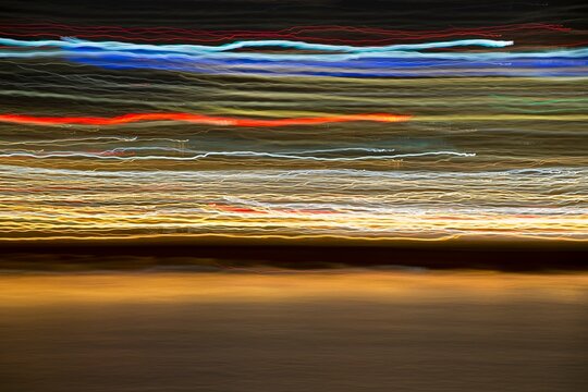 Long exposure abstract of Portland, Oregon skyline with colorful streaks of city lights reflecting across the Willamette River at night.