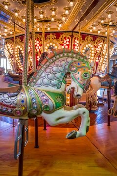 Close-up of a colorful carousel horse on a Merry Go Round decorated with jewels and ornate patterns, with bright lights and mirrors in the background. Seattle, Washington.