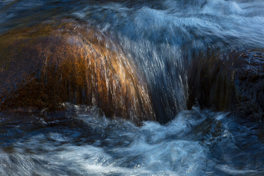 Long exposure of river water flowing over boulders and rocks