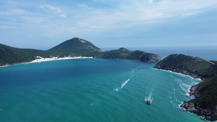 Aerial panoramic view of turquoise bay with boats and sandy beach surrounded by green hills in Brazil. Tropical coastline and calm ocean water, popular travel destination.