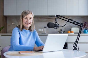 Senior woman actively creating content, producing her podcast episode with a microphone and laptop...