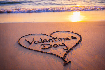 Valentines day message heart shape drawn on sandy beach at sunset with ocean waves in the background  romantic holiday concept