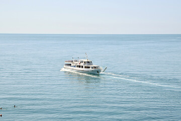 A summer seascape. A snow-white pleasure boat enters the port with tourists.

