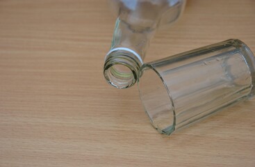 An empty alcohol bottle and an overturned glass on a wooden table. Concept of quitting drinking, Dry January challenge, and sobriety. The end of alcohol addiction and a new beginning. 
