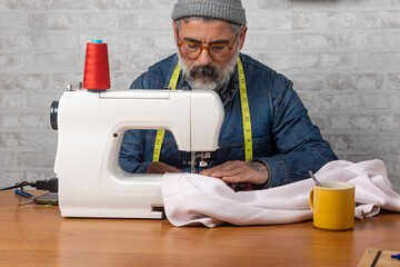 Male artisan tailoring garment using sewing machine
