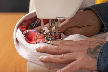 Person sewing fabric with machine creating new clothes