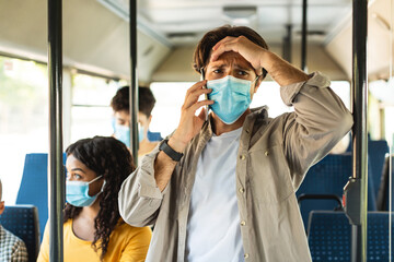Frustrated male in surgical mask feeling upset desperate talking on the phone having problems debt,...