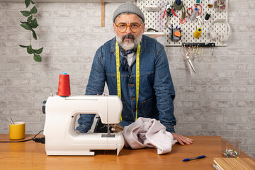 Mature male tailor standing in his clothing workshop
